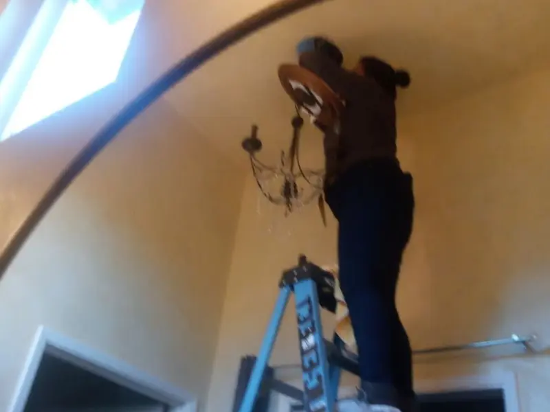 Electrician installing a chandelier in a Whitehall residence